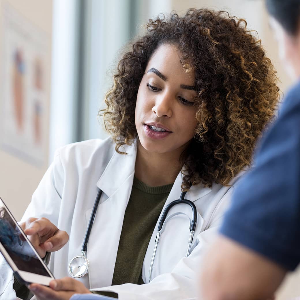A health practitioner sharing information on a tablet with a patient.