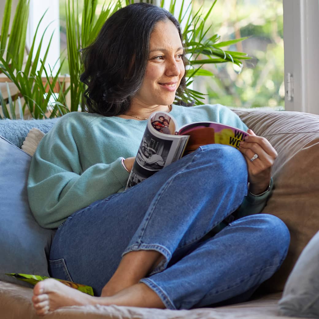 A person reading a magazine on their sofa.