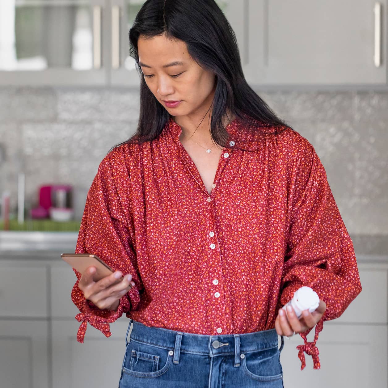 Someone requesting a refill on their cell phone while holding a prescription bottle.