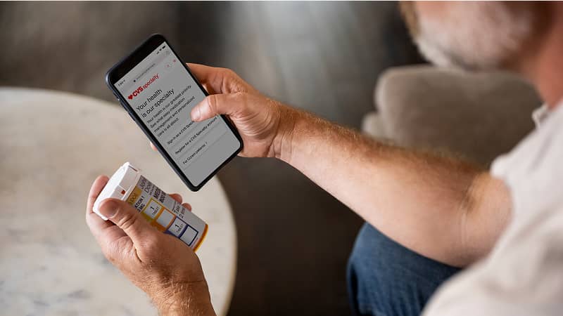 A person checking a prescription label on the CVS Specialty app.