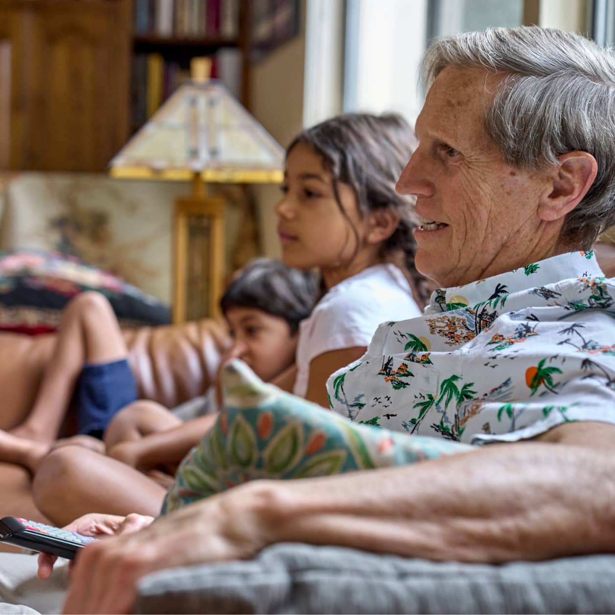 A family at home on the sofa, watching television.