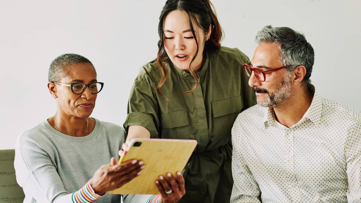 A practitioner pointing to a tablet screen as a pair of patients look on.