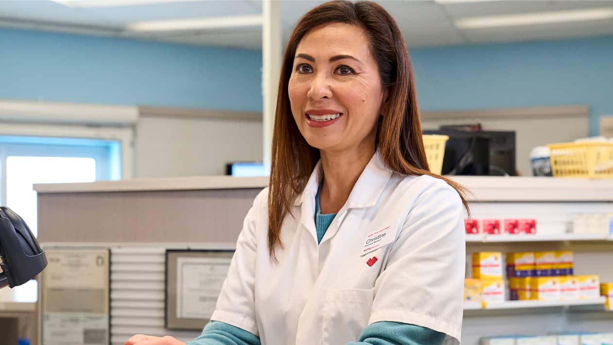 Someone looking at their cell phone screen with their laptop open as they sit in a coffeeshop