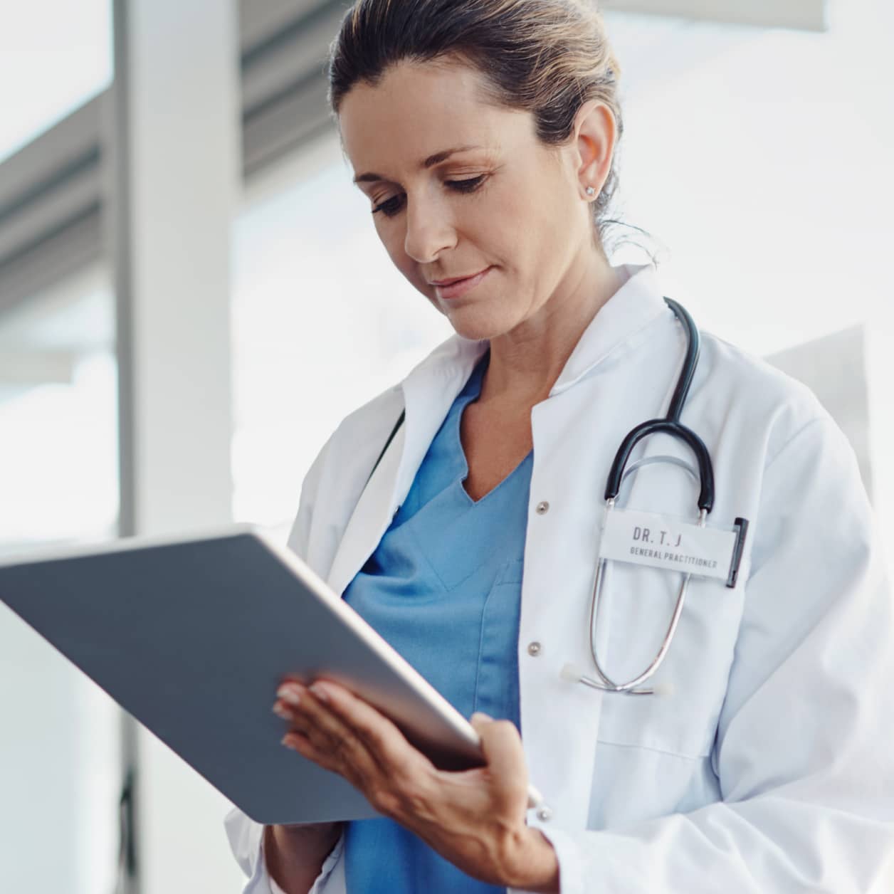 A practitioner looks down at a tablet screen in a hallway