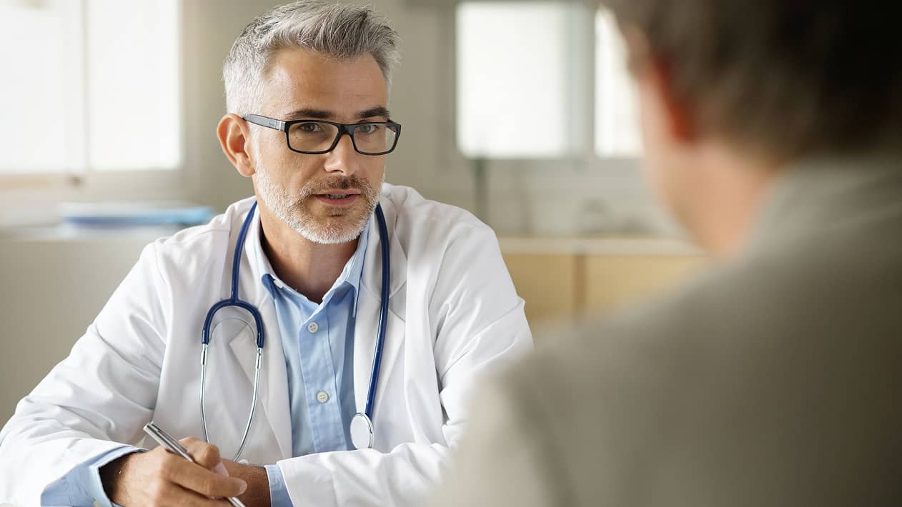A health care provider wearing a stethoscope and talking to a patient
