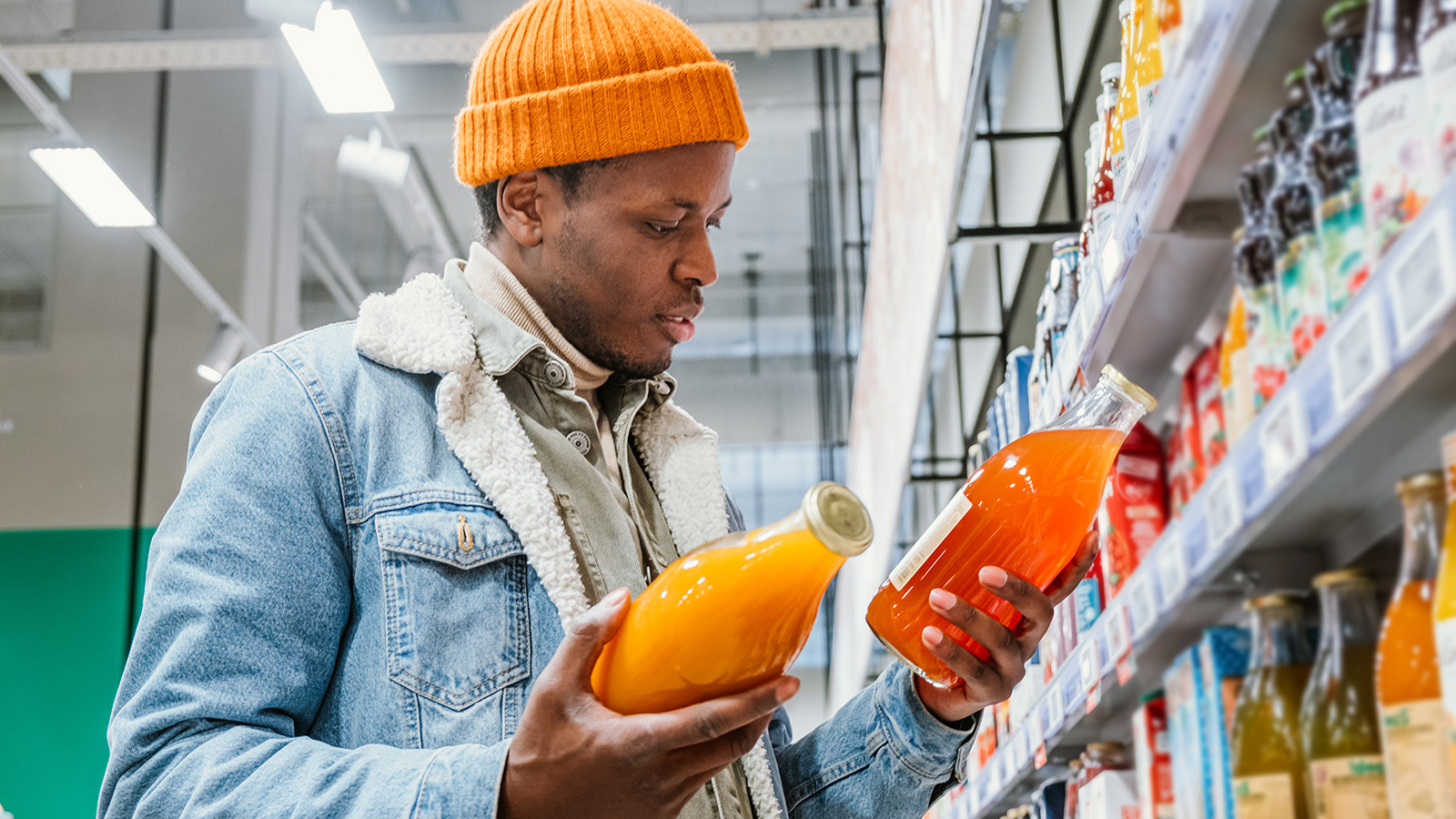 Shopper comparing beverage bottles in a store aisle.