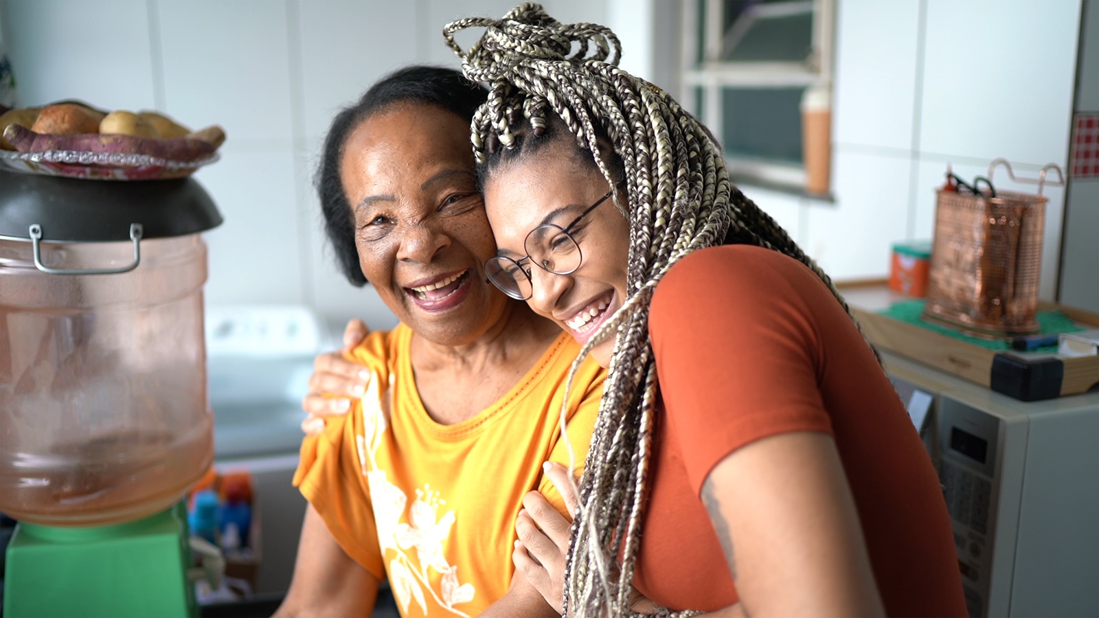 Two women sharing a supportive moment in a kitchen setting.