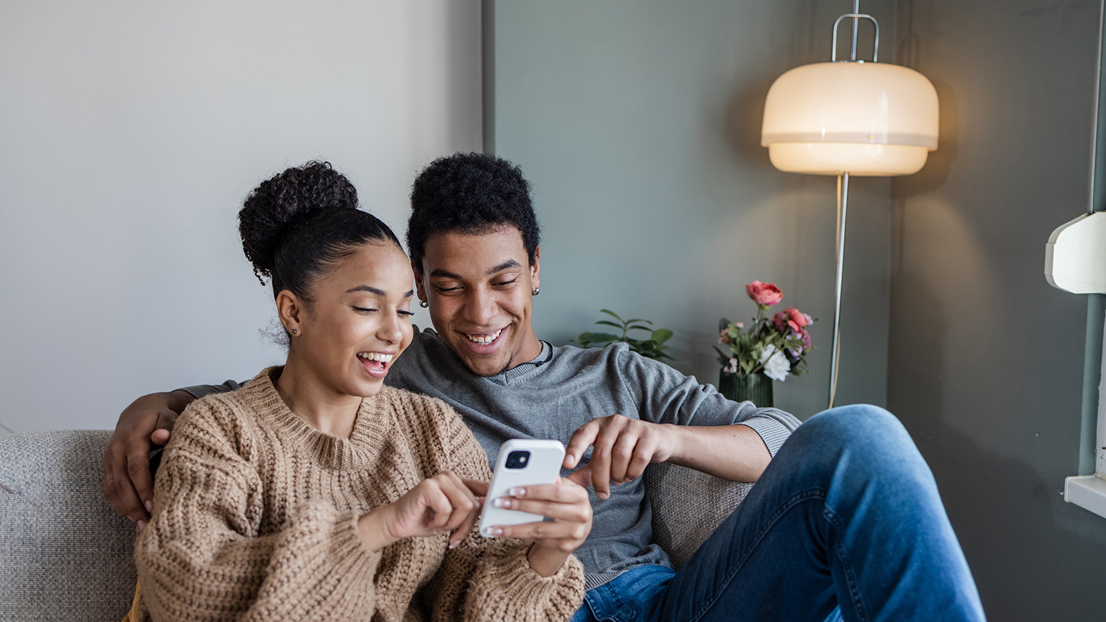 Couple looking at a phone together on a couch.