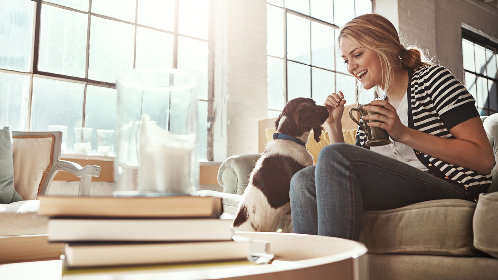 Woman enjoying coffee with a dog in a cozy living room.