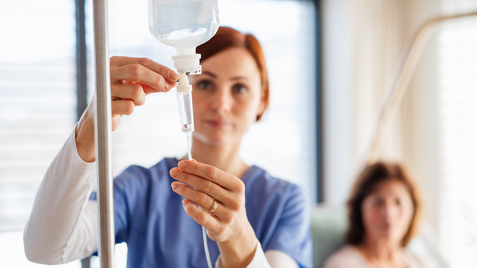 Nurse adjusting an IV drip in an infusion suite setting.