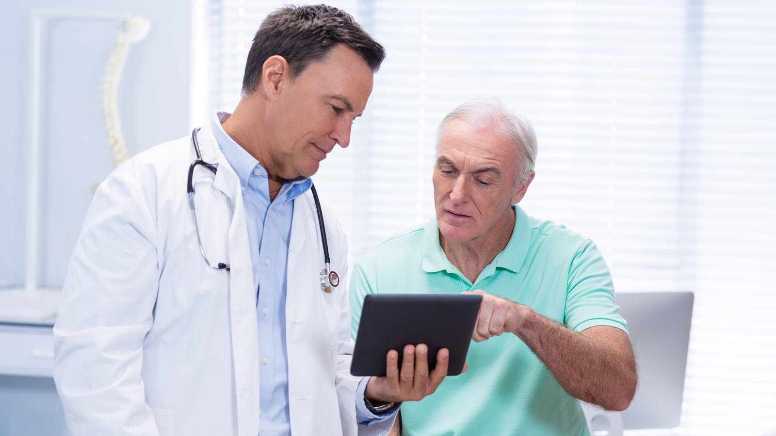 Doctor and patient discussing information on a tablet in a medical office.
