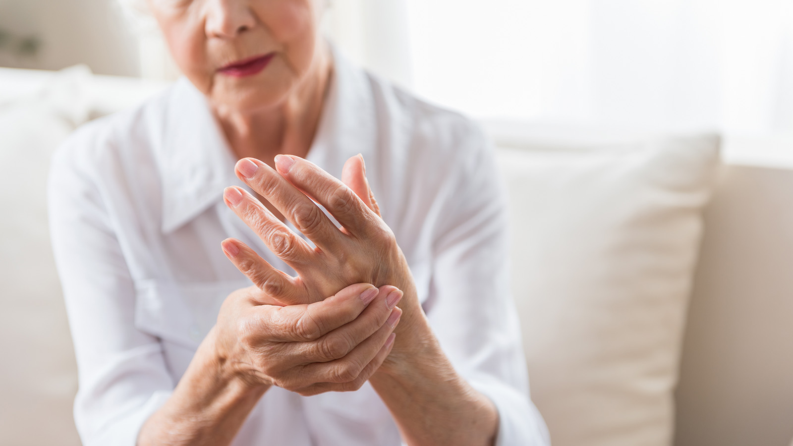 An elderly person holding their wrist in discomfort