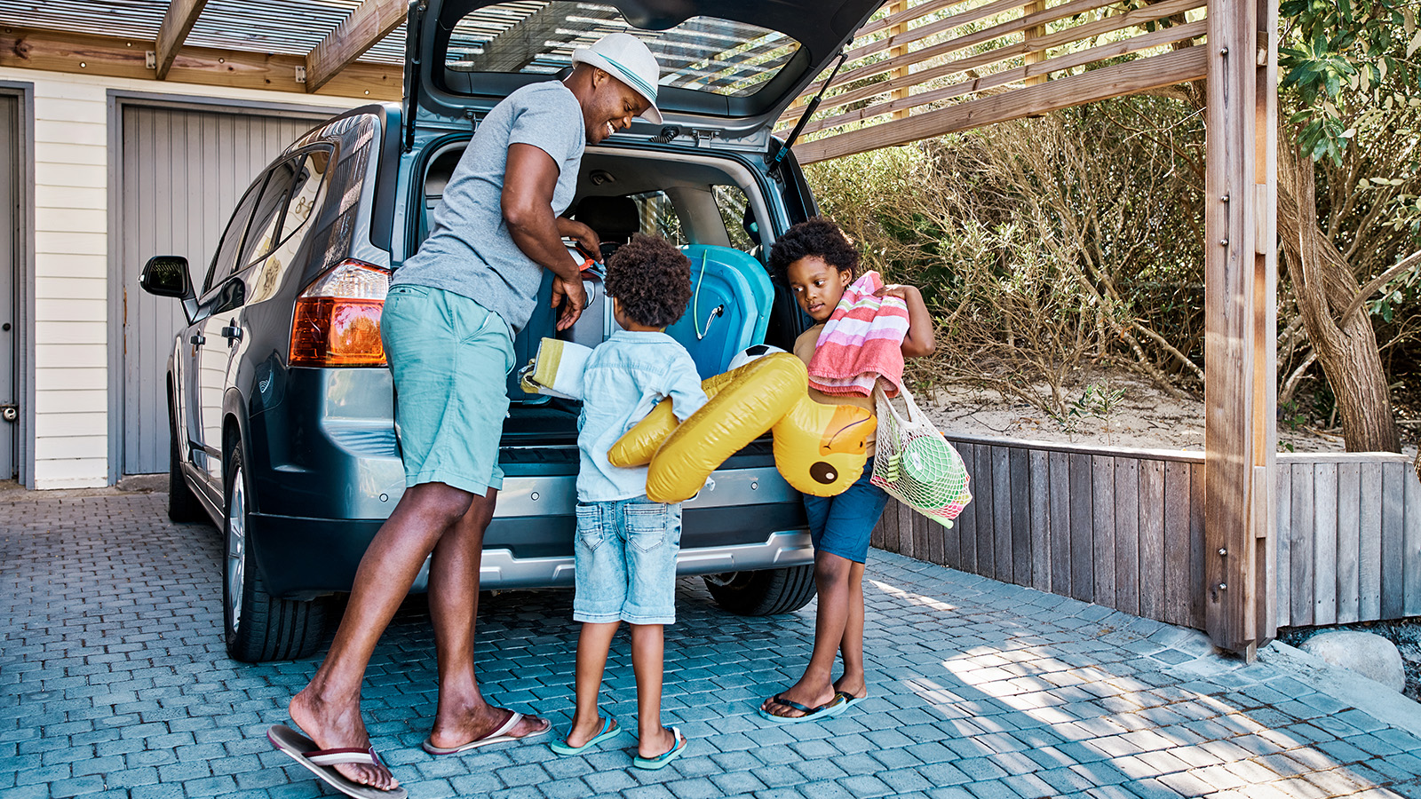 A family loads a car with beach gear, including inflatable toys and bags, preparing for a fun outing.