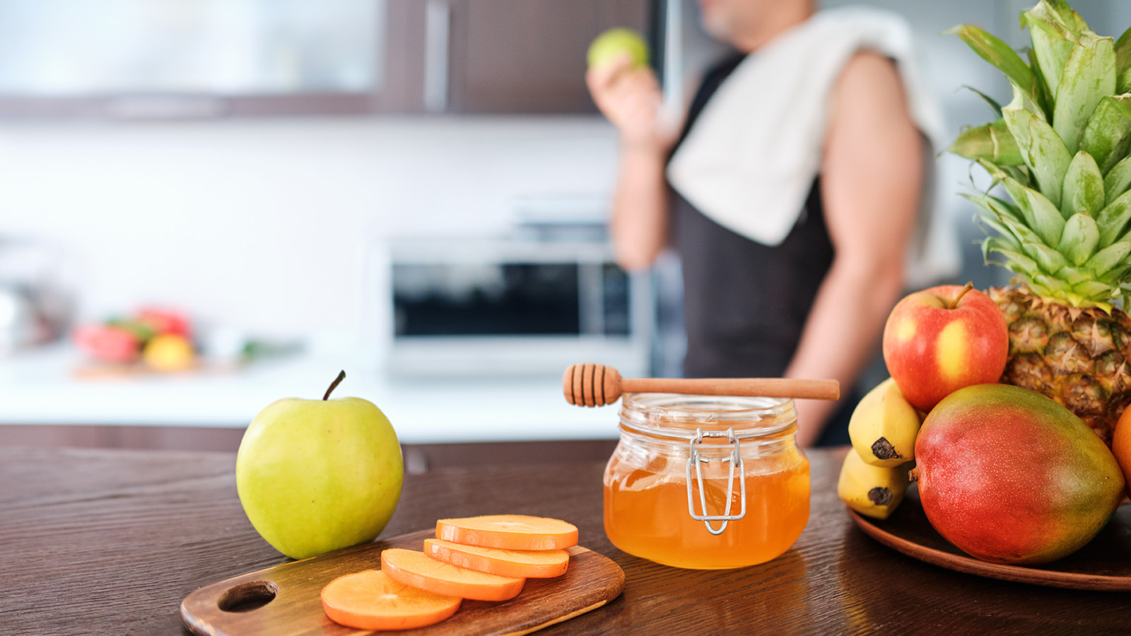 A kitchen scene features fresh fruits and honey, suggesting healthy eating and culinary preparation in a home environment.