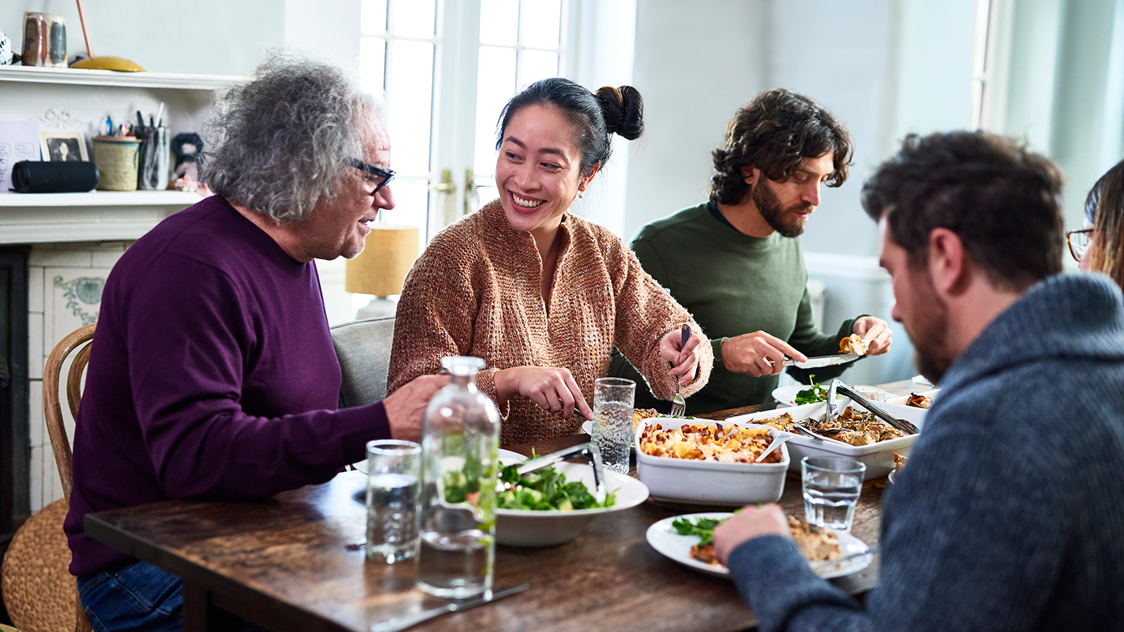 A group of people is seated at a dining table, enjoying a meal with various dishes and drinks.
