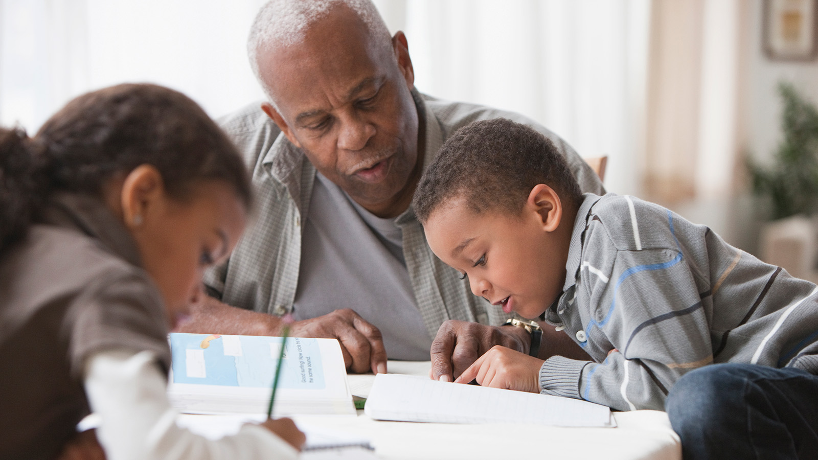 An adult helping children with their homework at a table