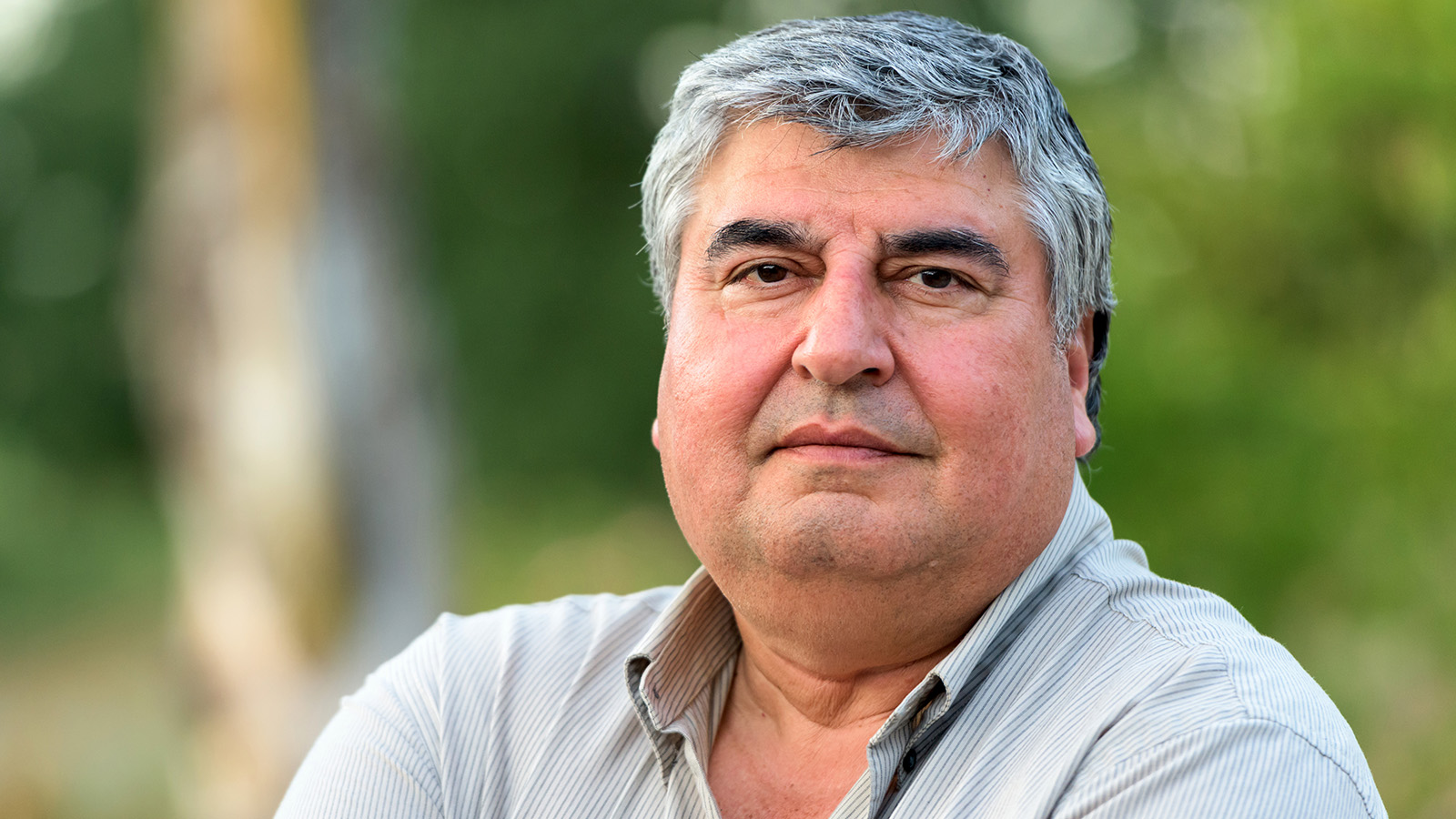 A man looking directly at the camera outdoors