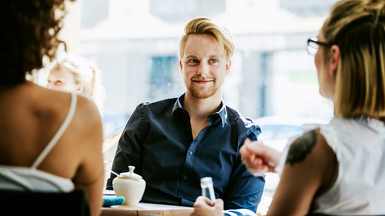 A person sitting at a table with friends in a café