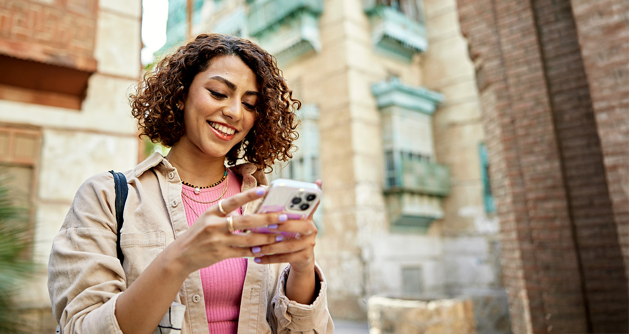 A woman using her phone while standing outside near buildings