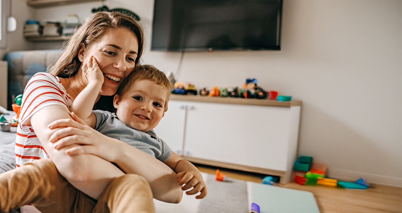 A mother holding her child while sitting on a couch