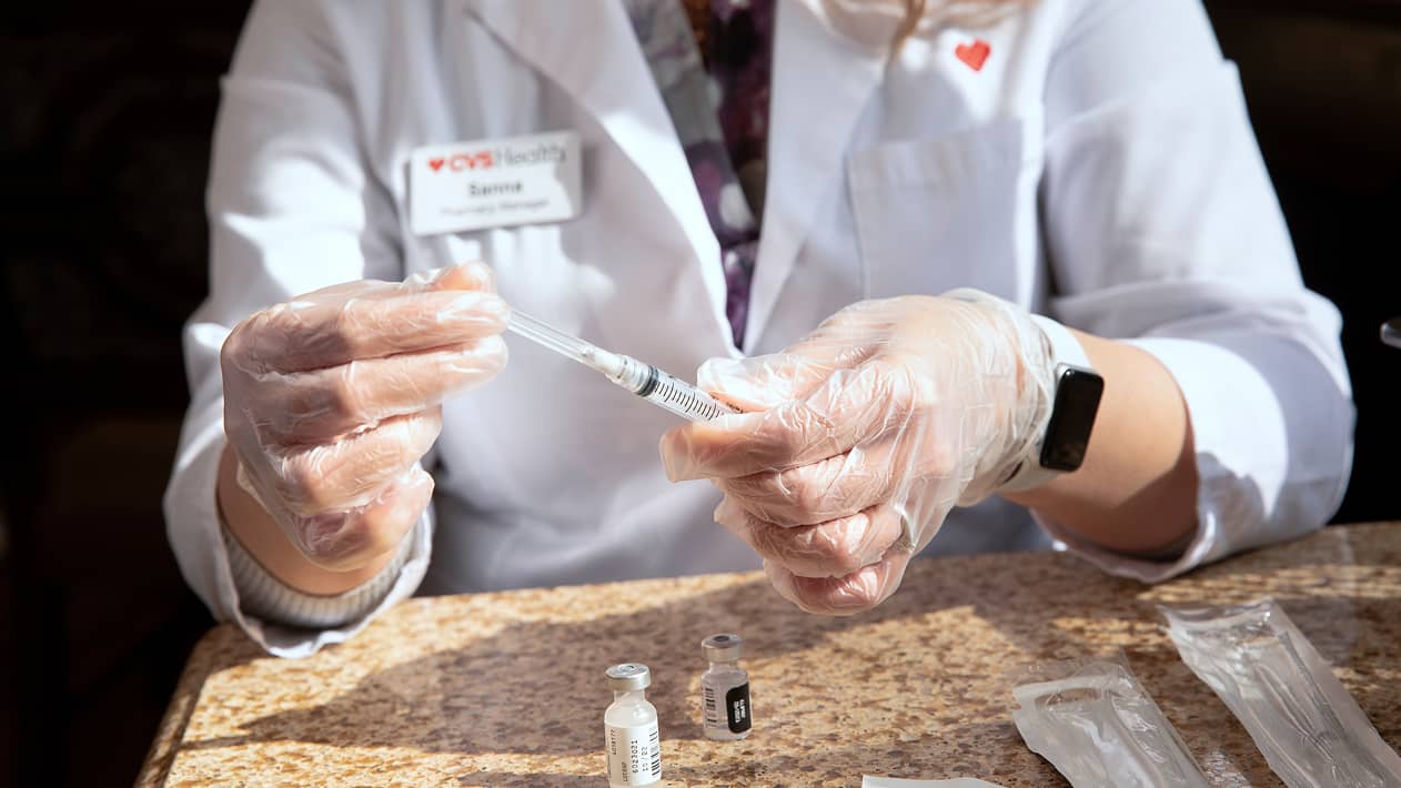 A CVS practitioner preparing a syringe.